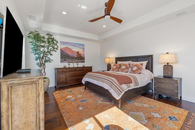 bedroom featuring ceiling fan, dark hardwood / wood-style flooring, and a raised ceiling