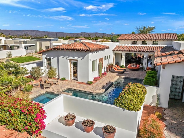 rear view of property featuring a patio, a mountain view, and a pool with hot tub