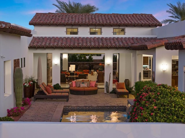 back house at dusk with an outdoor hangout area and a patio