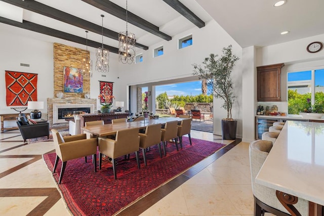 tiled dining space with a large fireplace, a healthy amount of sunlight, beam ceiling, and a chandelier