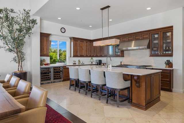 kitchen with tasteful backsplash, sink, a breakfast bar area, hanging light fixtures, and a center island with sink