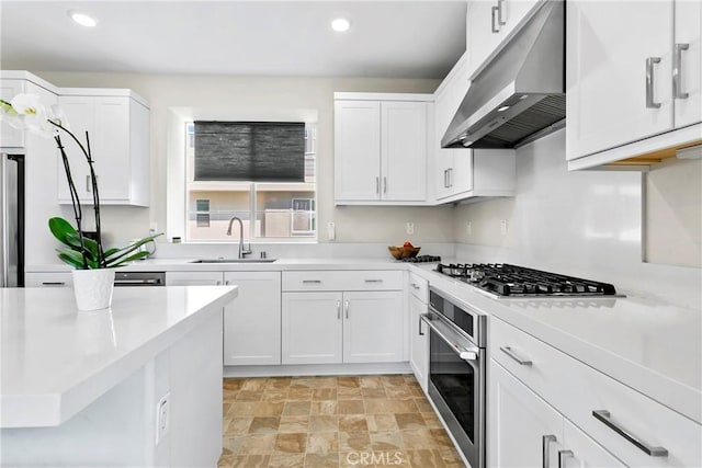 kitchen featuring stainless steel appliances, wall chimney exhaust hood, white cabinets, and sink