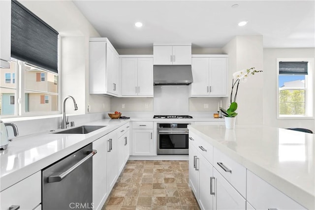 kitchen with exhaust hood, sink, stainless steel appliances, and white cabinetry