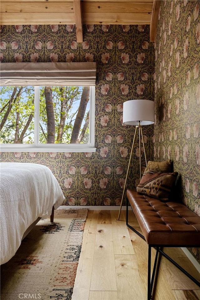 bedroom featuring beam ceiling, multiple windows, and hardwood / wood-style flooring