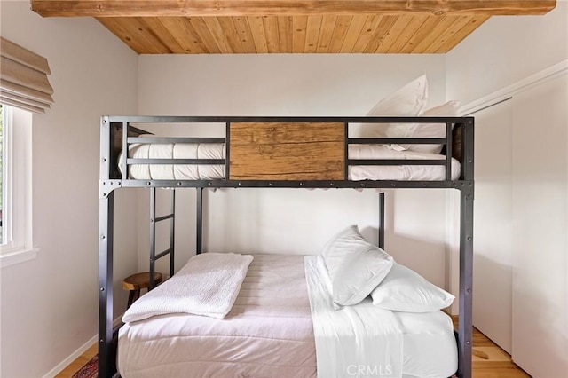 bedroom featuring wooden ceiling, multiple windows, hardwood / wood-style floors, and beamed ceiling