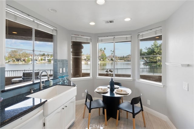 interior space with light hardwood / wood-style floors, a water view, and sink