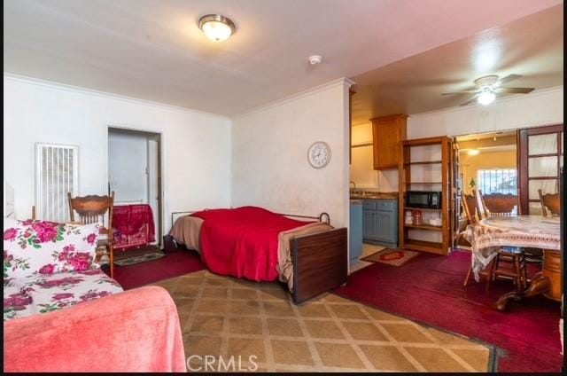 carpeted bedroom with ceiling fan, crown molding, and ensuite bath