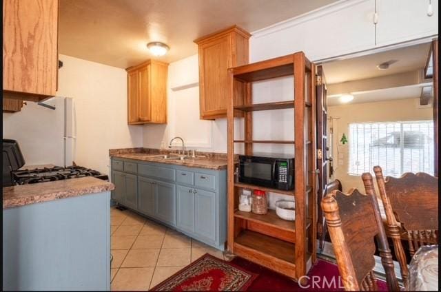 kitchen featuring white fridge, gray cabinets, stove, light tile patterned flooring, and sink