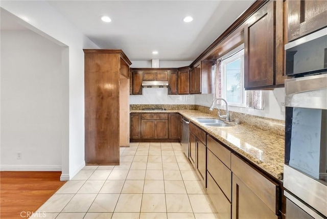 kitchen featuring light stone countertops, sink, appliances with stainless steel finishes, and light wood-type flooring