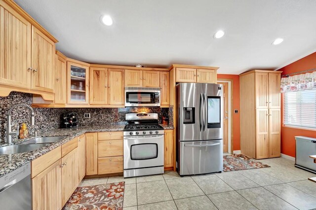 kitchen featuring sink, light brown cabinets, stainless steel appliances, and dark stone counters