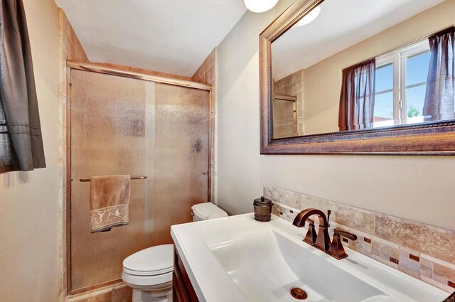 bathroom featuring toilet, a shower with door, and vanity