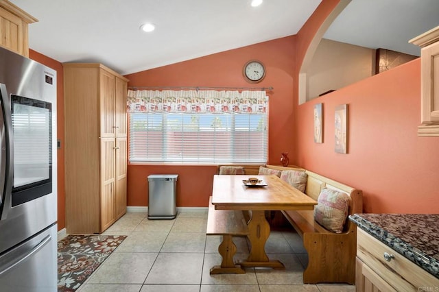 tiled dining space featuring vaulted ceiling