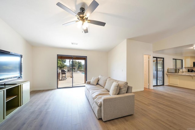 living room with ceiling fan and light hardwood / wood-style flooring