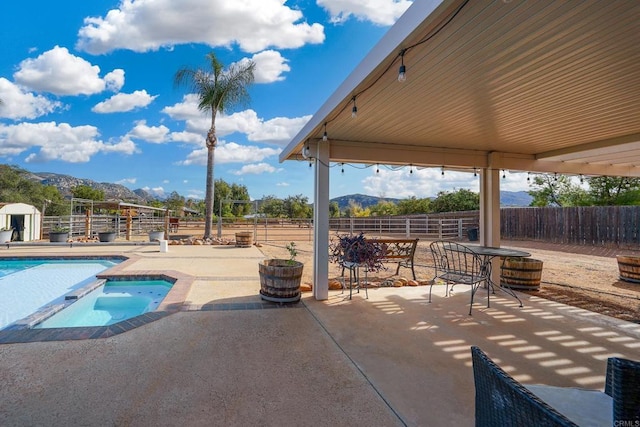 view of swimming pool with an in ground hot tub, a mountain view, and a patio area