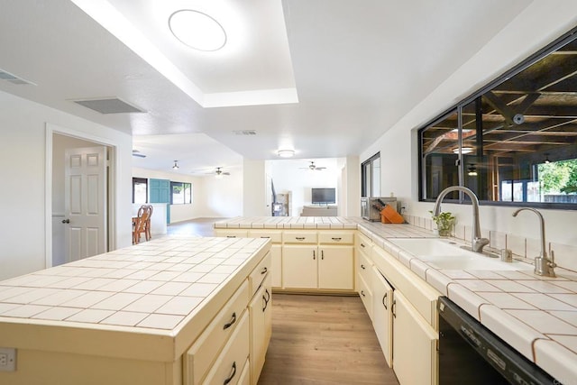 kitchen featuring ceiling fan, tile countertops, sink, and black dishwasher