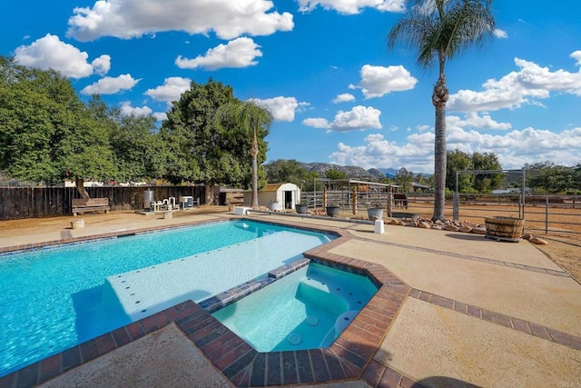 view of pool featuring a storage shed, a mountain view, a patio, and an in ground hot tub