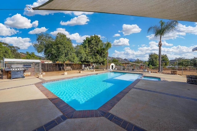 view of swimming pool featuring a patio, an in ground hot tub, and grilling area