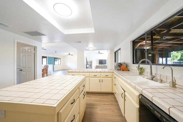 kitchen featuring a center island, sink, black dishwasher, and tile counters