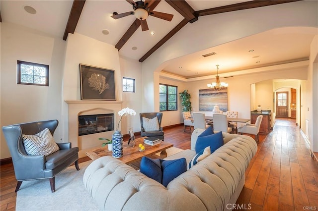 living room with hardwood / wood-style flooring, lofted ceiling with beams, and ceiling fan with notable chandelier