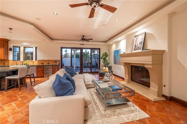 living room with ceiling fan and a raised ceiling