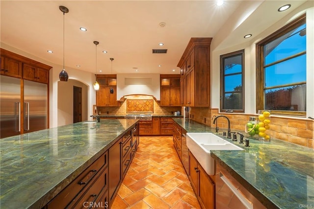 kitchen with custom exhaust hood, stainless steel appliances, backsplash, decorative light fixtures, and sink