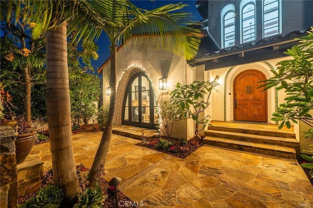 view of exterior entry with a patio area and french doors