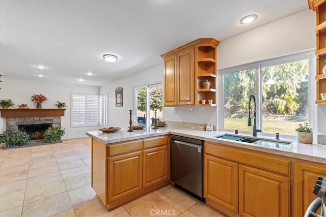 kitchen featuring a fireplace, stainless steel dishwasher, kitchen peninsula, a wealth of natural light, and sink