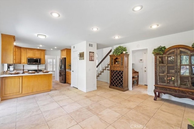 kitchen featuring light tile patterned floors, black fridge, and kitchen peninsula