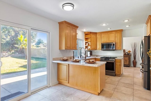 kitchen with kitchen peninsula, appliances with stainless steel finishes, sink, and light tile patterned flooring