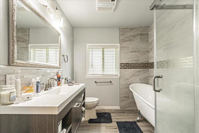 full bathroom with toilet, vanity, backsplash, and independent shower and bath