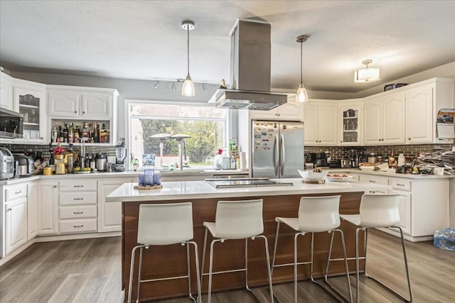 kitchen featuring decorative light fixtures, stainless steel fridge, island exhaust hood, and a center island