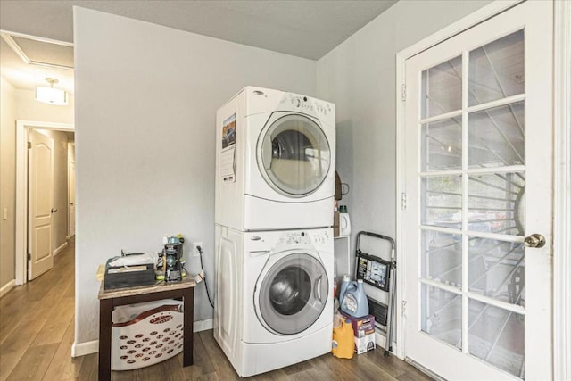 laundry room with dark wood-type flooring and stacked washer / drying machine