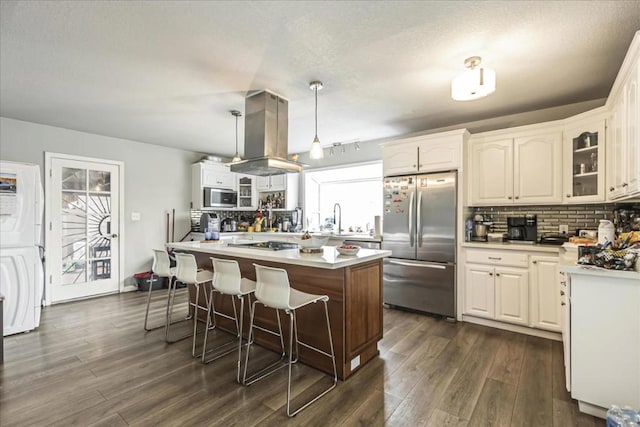 kitchen featuring island range hood, stainless steel appliances, backsplash, hanging light fixtures, and a center island