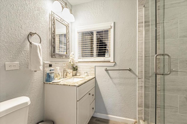 bathroom featuring decorative backsplash, toilet, walk in shower, and vanity