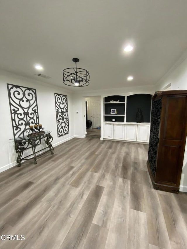 interior space with built in shelves, crown molding, and hardwood / wood-style floors