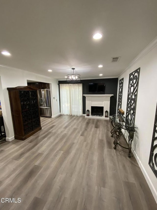 living room featuring crown molding, wood-type flooring, and a notable chandelier