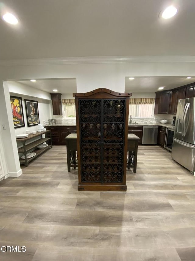 kitchen featuring dark brown cabinetry, appliances with stainless steel finishes, and light wood-type flooring