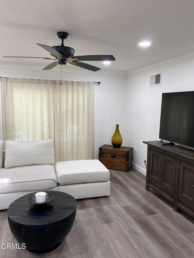 living room featuring ceiling fan, ornamental molding, and light hardwood / wood-style flooring