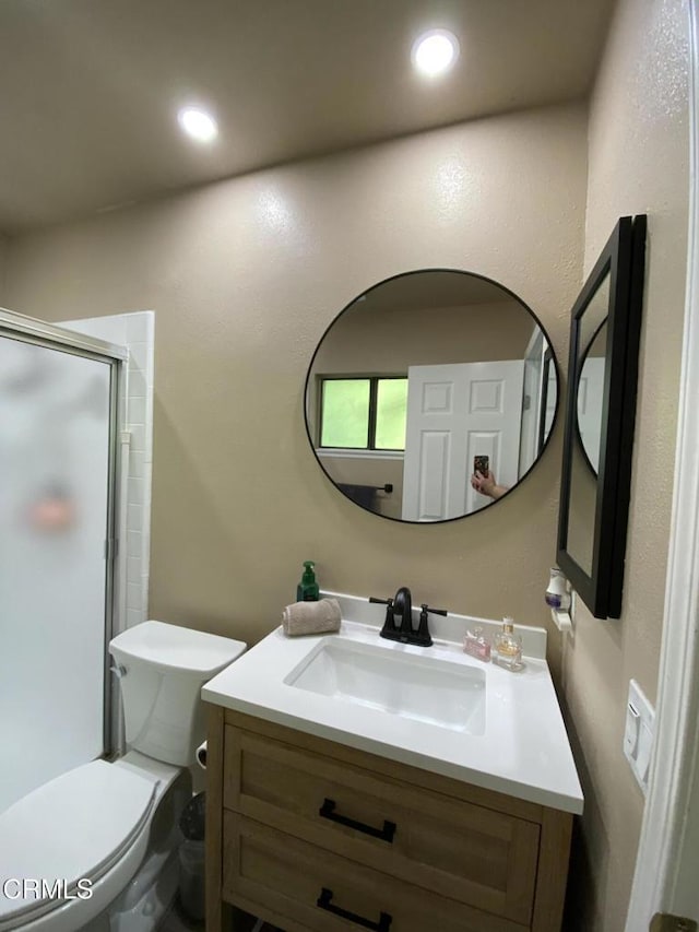 bathroom featuring vanity, toilet, and a shower with door