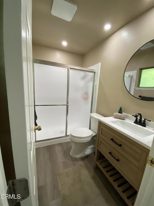 bathroom with an enclosed shower, vanity, toilet, and hardwood / wood-style floors