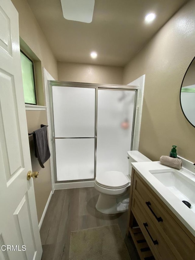 bathroom with an enclosed shower, vanity, wood-type flooring, and toilet