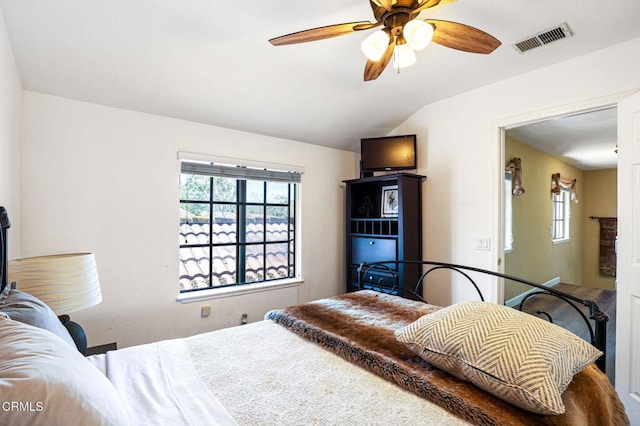 bedroom with visible vents, a fireplace, lofted ceiling, and a ceiling fan