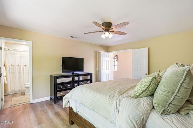 bedroom featuring visible vents, ceiling fan, baseboards, light wood-style floors, and ensuite bath