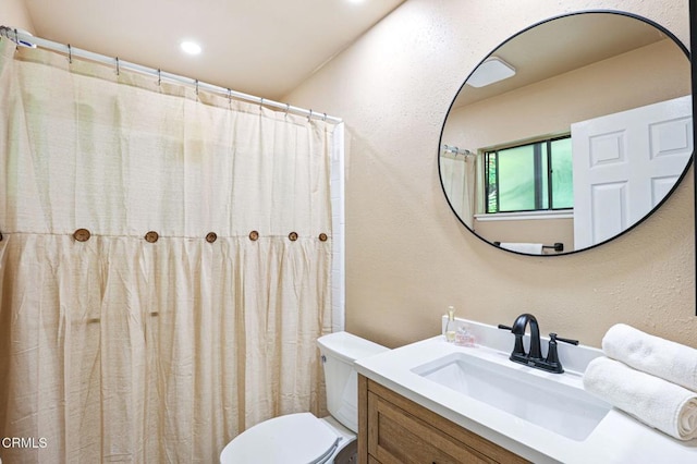 bathroom featuring toilet, vanity, and a textured wall