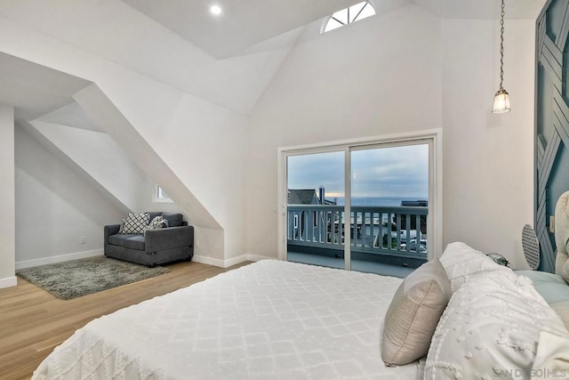 bedroom featuring hardwood / wood-style floors, access to outside, and high vaulted ceiling