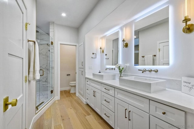 bathroom featuring hardwood / wood-style flooring, vanity, toilet, and walk in shower