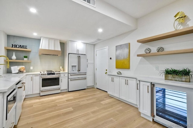 kitchen featuring white cabinetry, white appliances, and wall chimney range hood