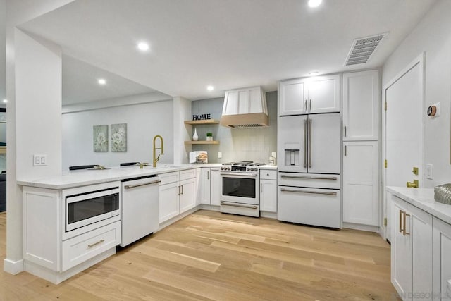 kitchen featuring built in appliances, white cabinetry, light hardwood / wood-style floors, and premium range hood