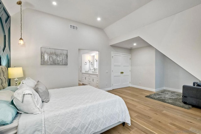 bedroom with hardwood / wood-style flooring, lofted ceiling, and connected bathroom