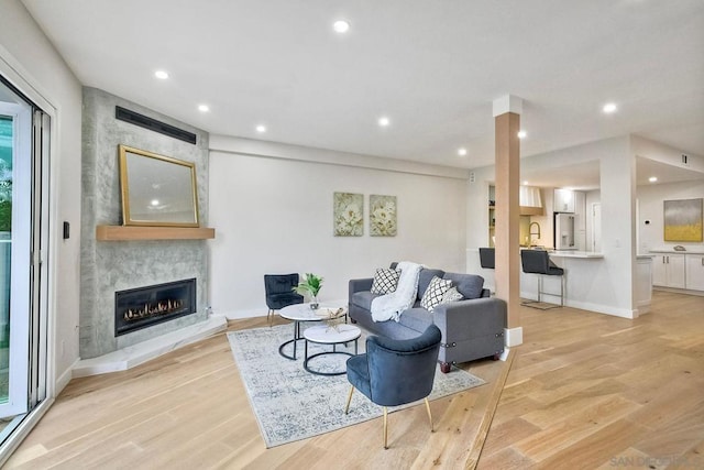 living room featuring light hardwood / wood-style floors and a large fireplace